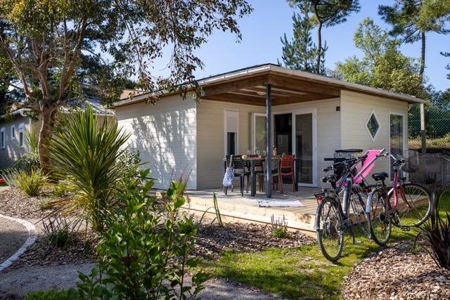 Chalet avec terrasse et vélos dans un jardin.