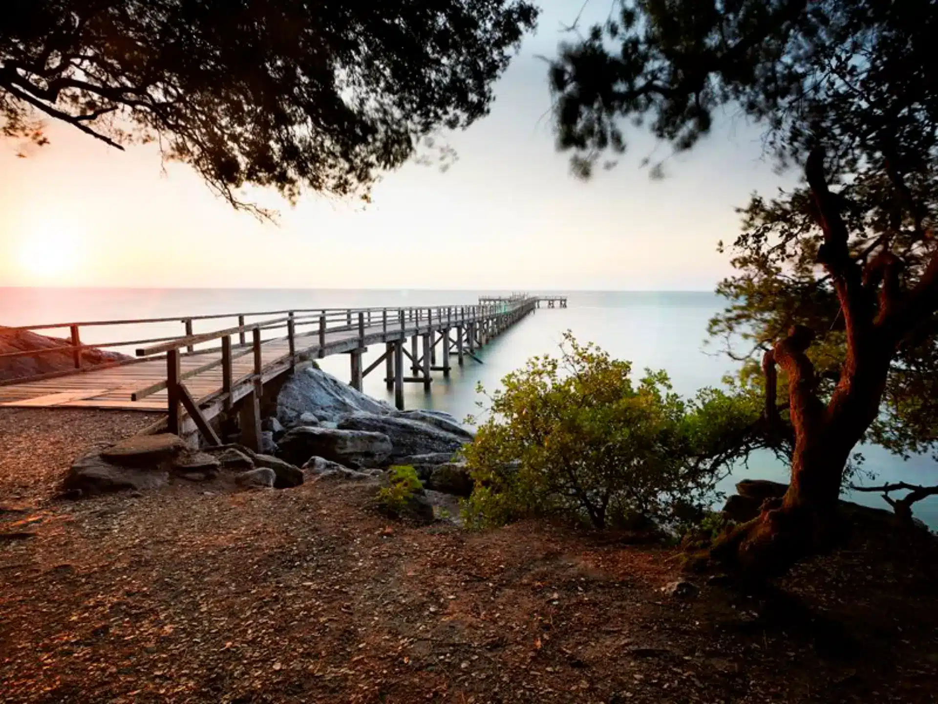 Ponton en bois au bord de l'eau au coucher.