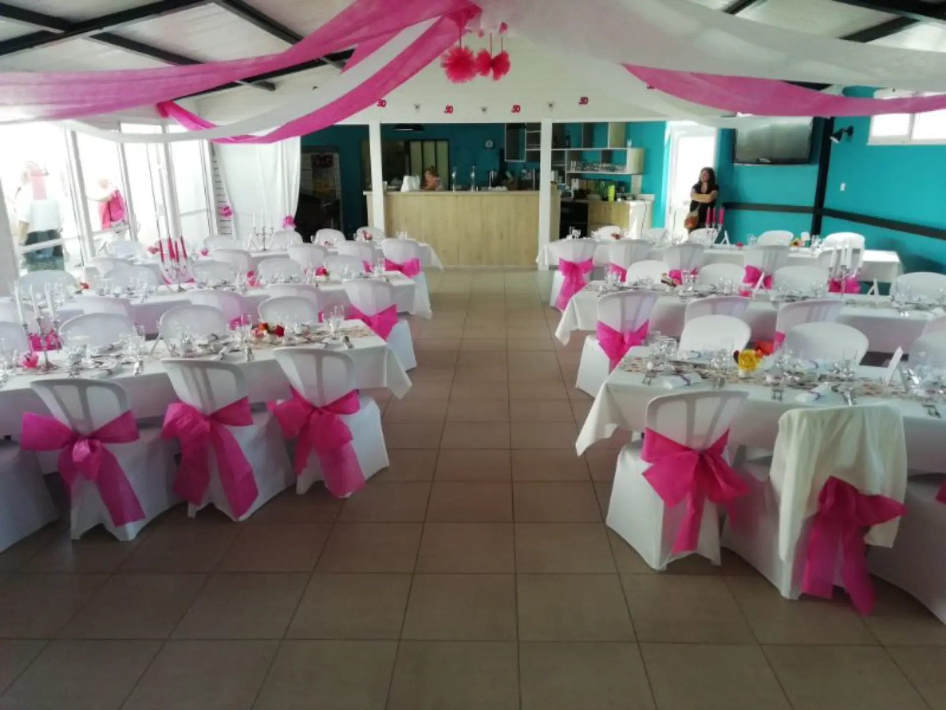 Salle de réception décorée avec nappes blanches et rubans roses.