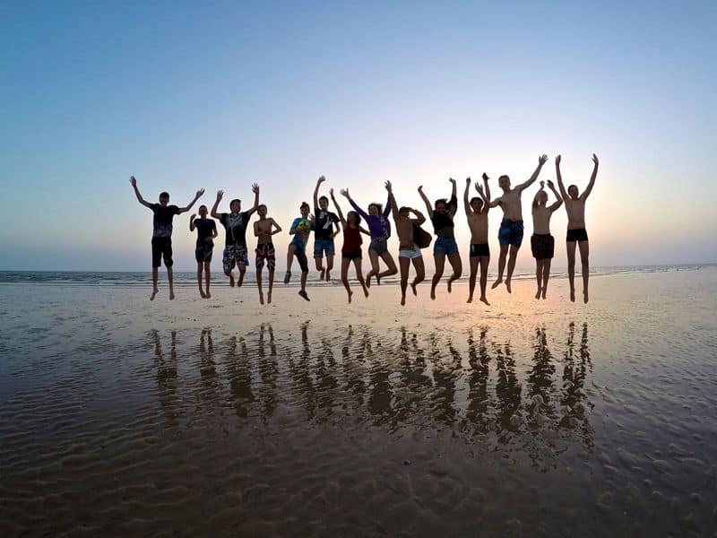 Groupe de personnes sautant joyeusement sur la plage.