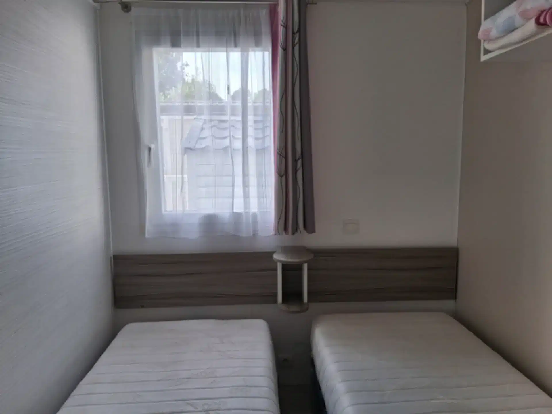 Chambre avec deux lits simples près de la fenêtre.