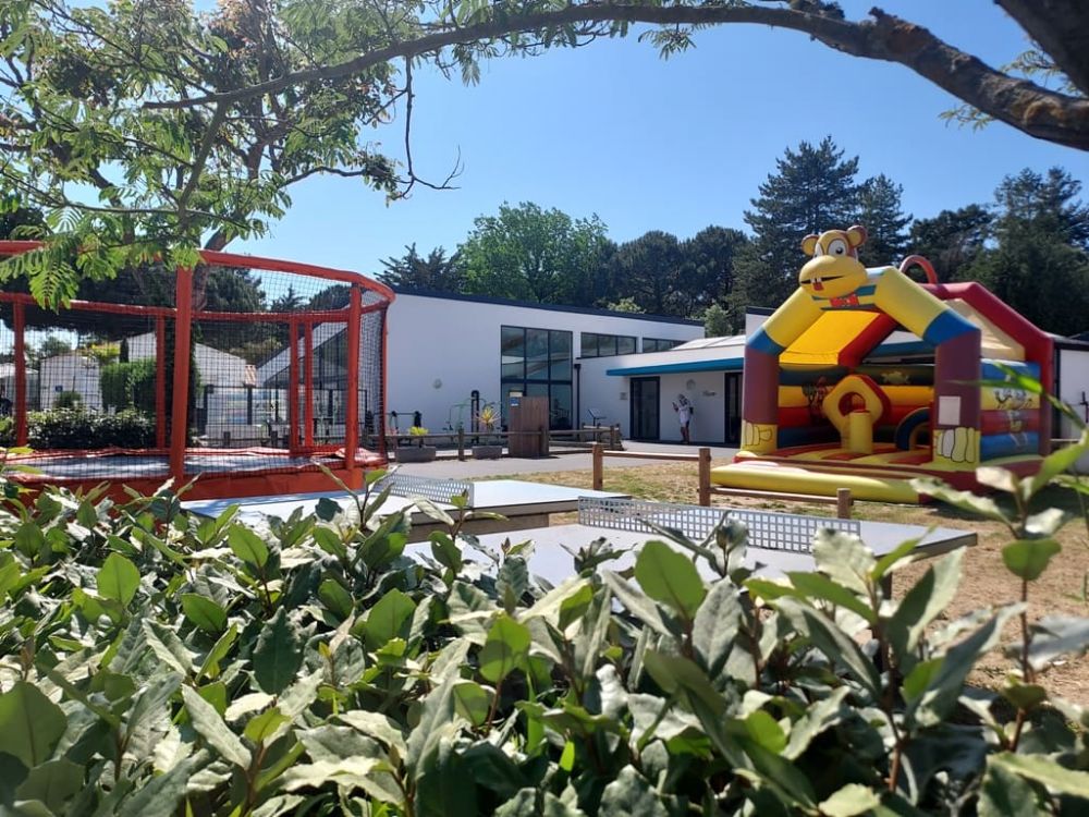 Aire de jeux extérieure avec trampoline et château gonflable.