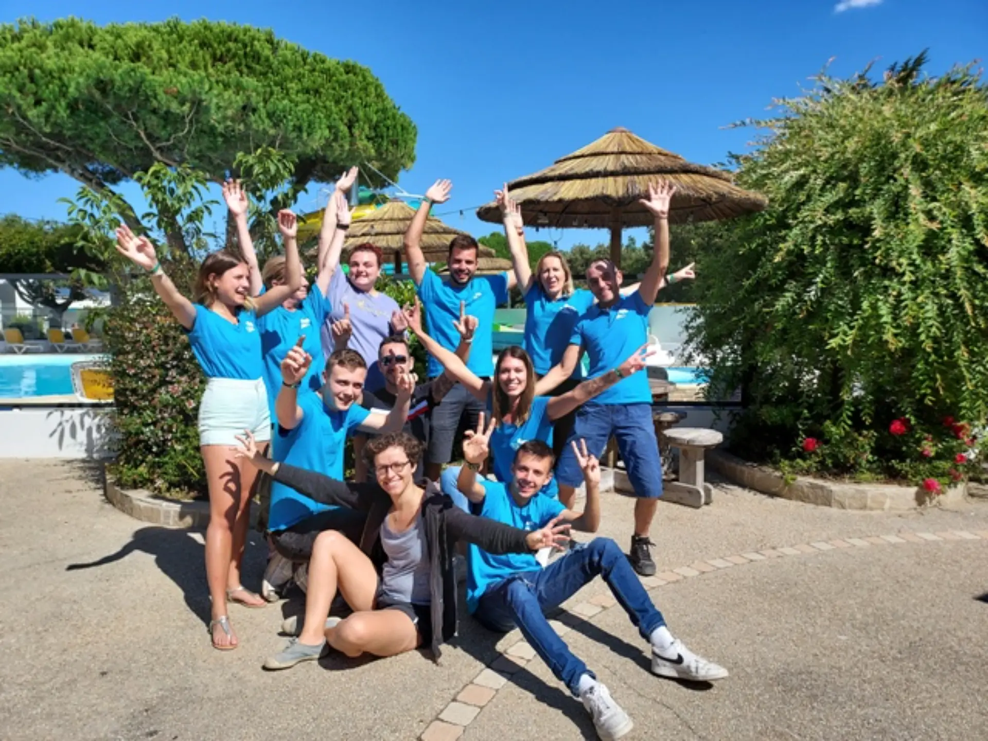 Groupe joyeux au soleil, bras levés, sourires heureux.