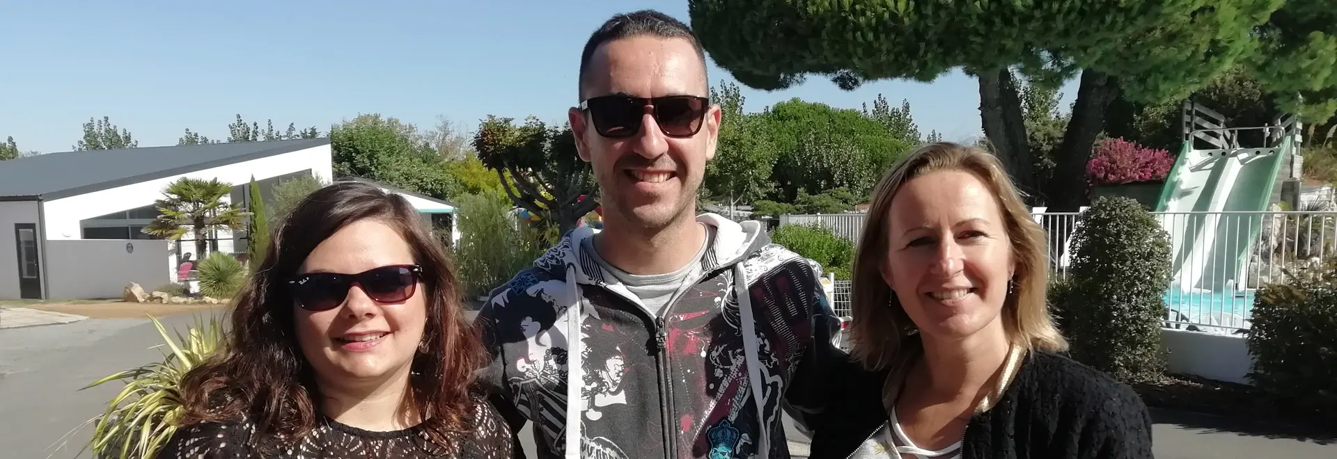 Trois personnes souriantes devant un toboggan aquatique.