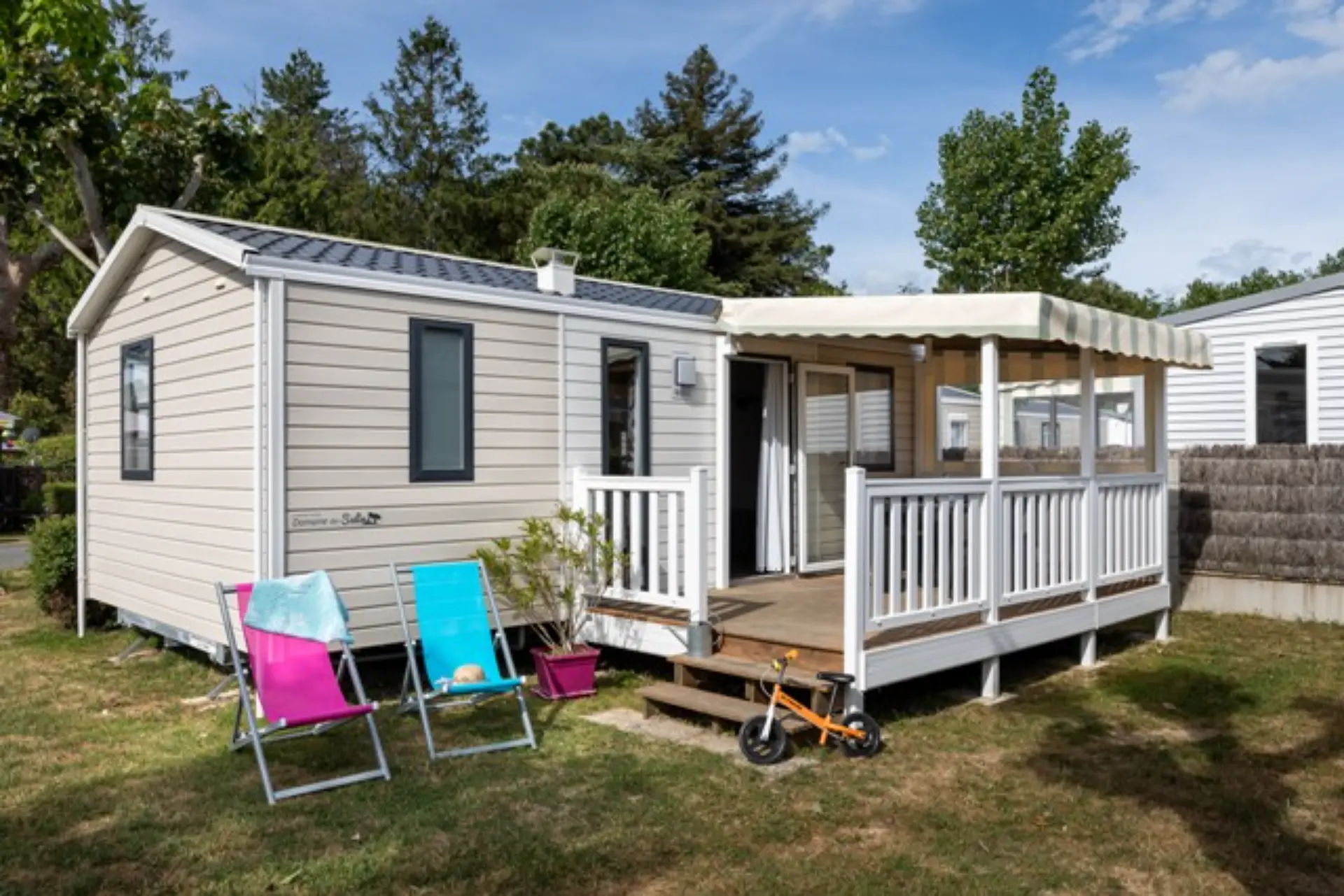Mobil-home avec terrasse et chaises longues colorées.