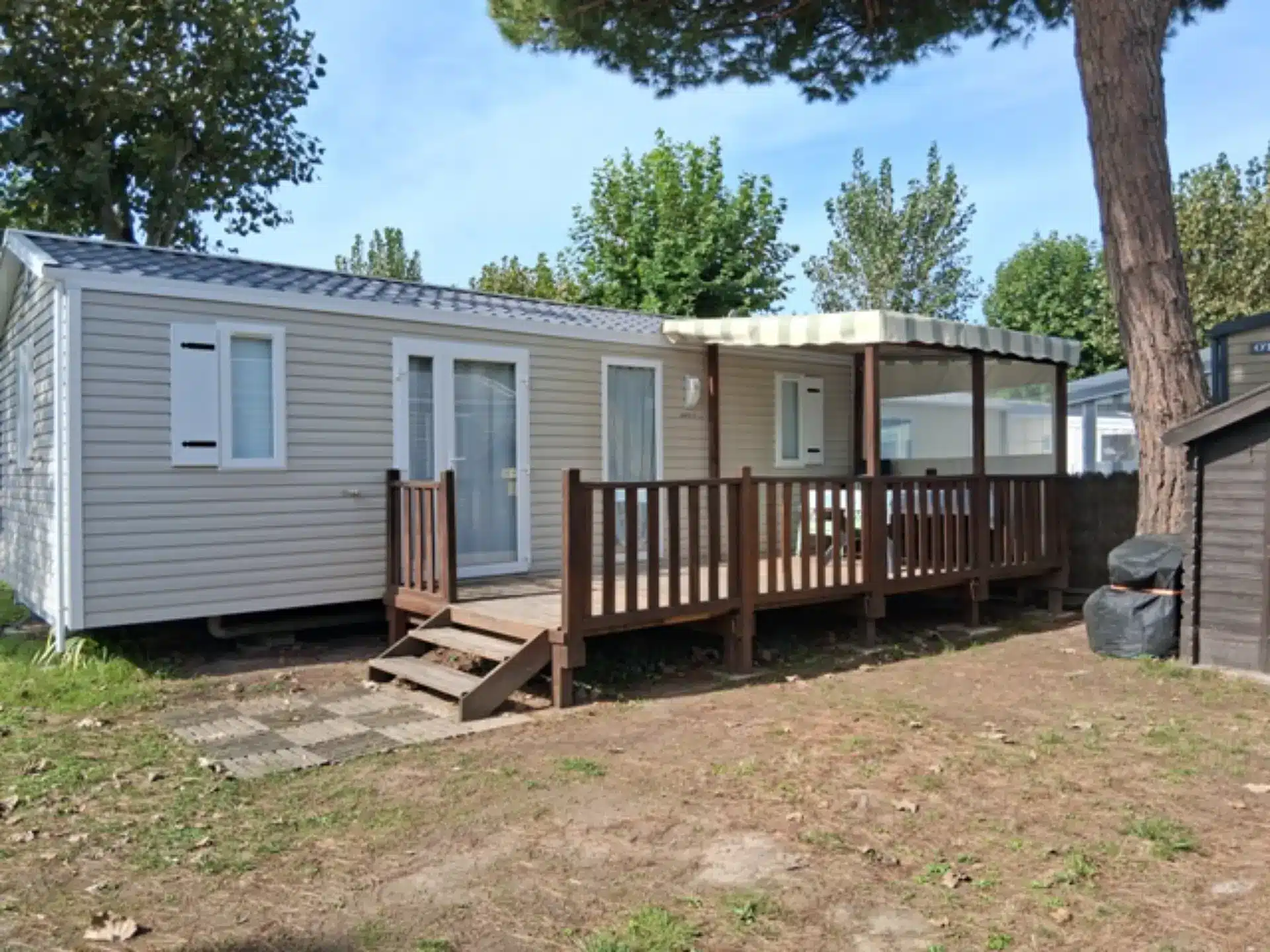 Mobil-home avec terrasse en bois ombragée.