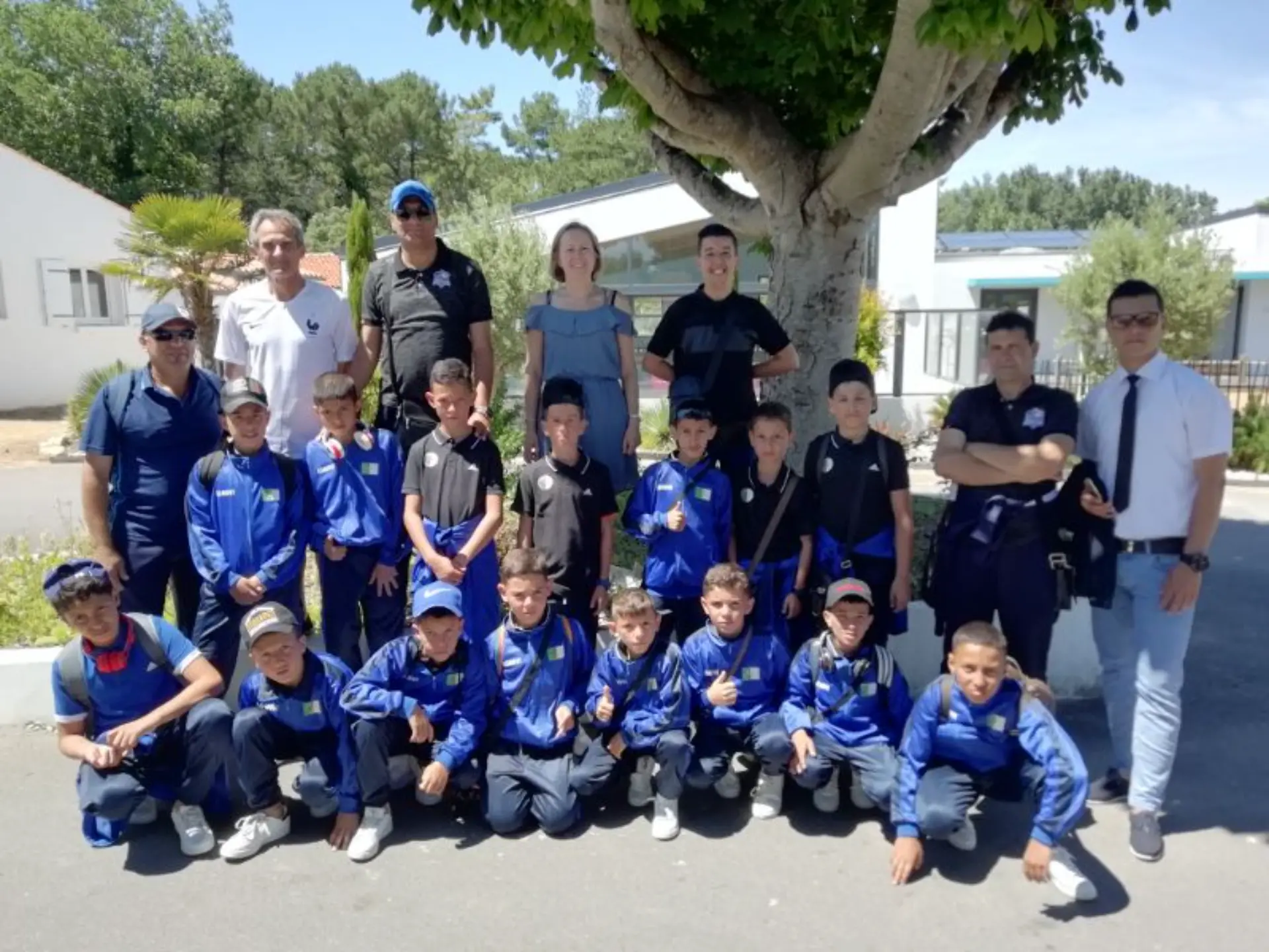 Équipe de football junior posant devant un arbre.