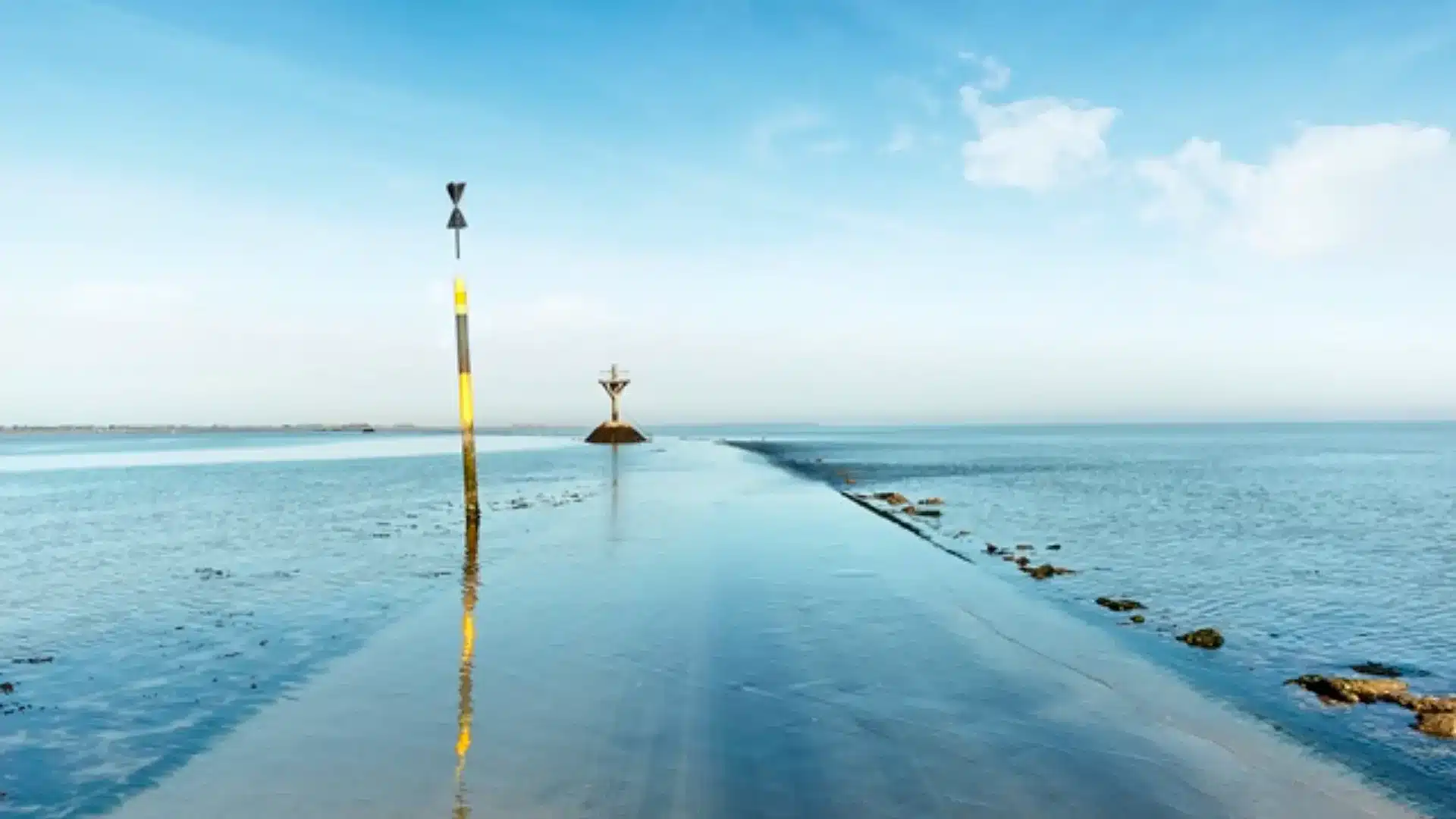 Route submersible à marée haute sous ciel bleu.