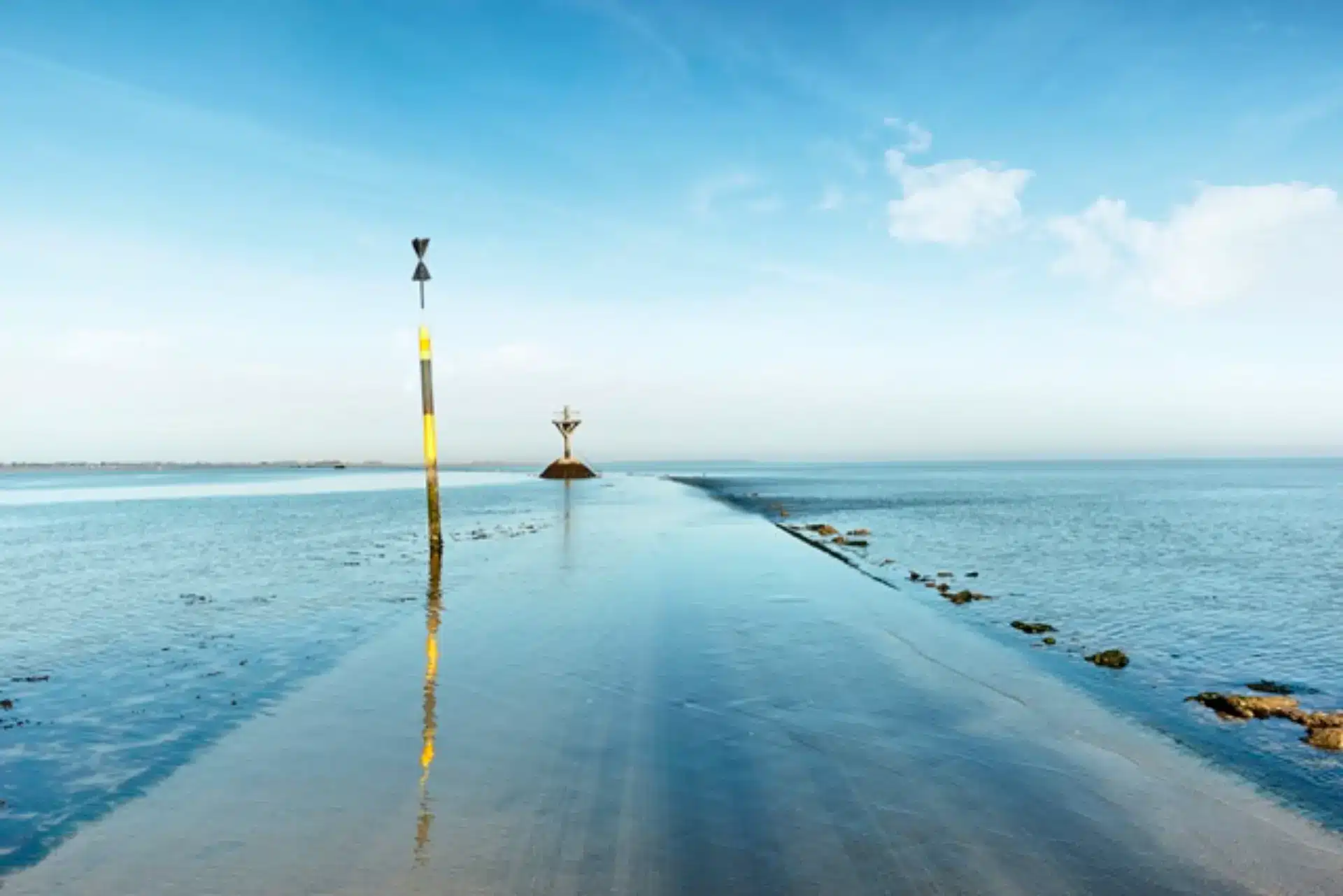 Route submersible à marée haute sous ciel bleu.