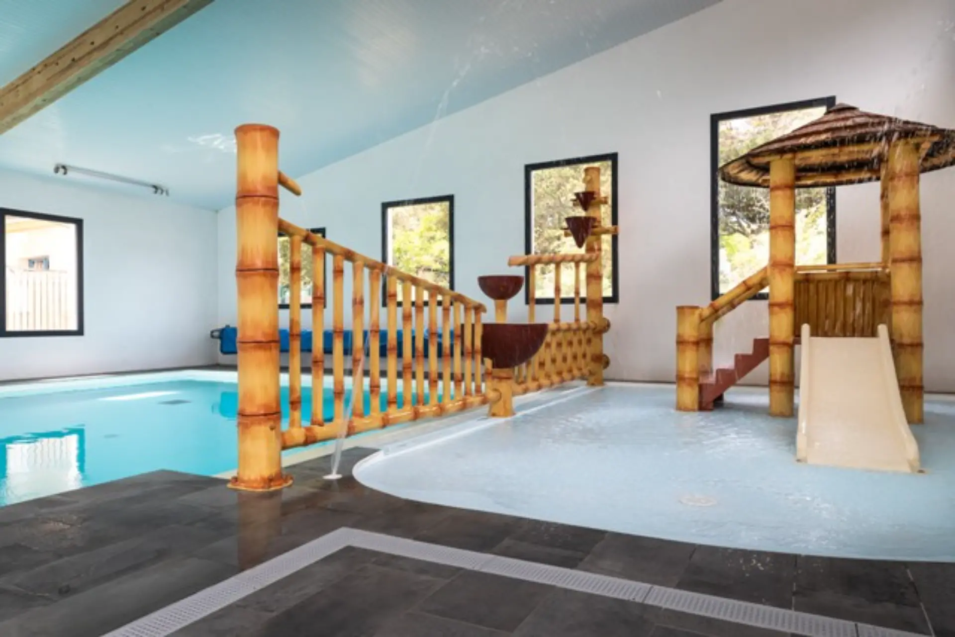 Piscine intérieure avec toboggan et jets d'eau.