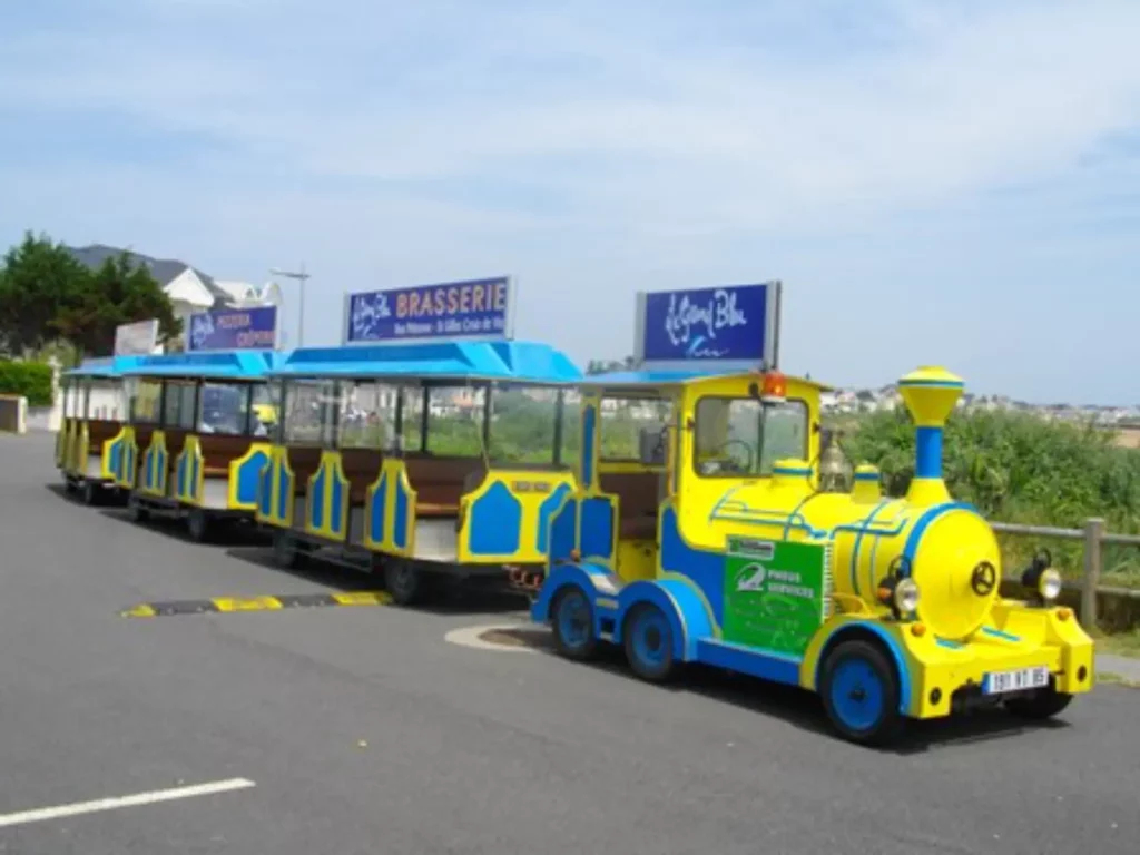 Petit train touristique jaune et bleu sur route.