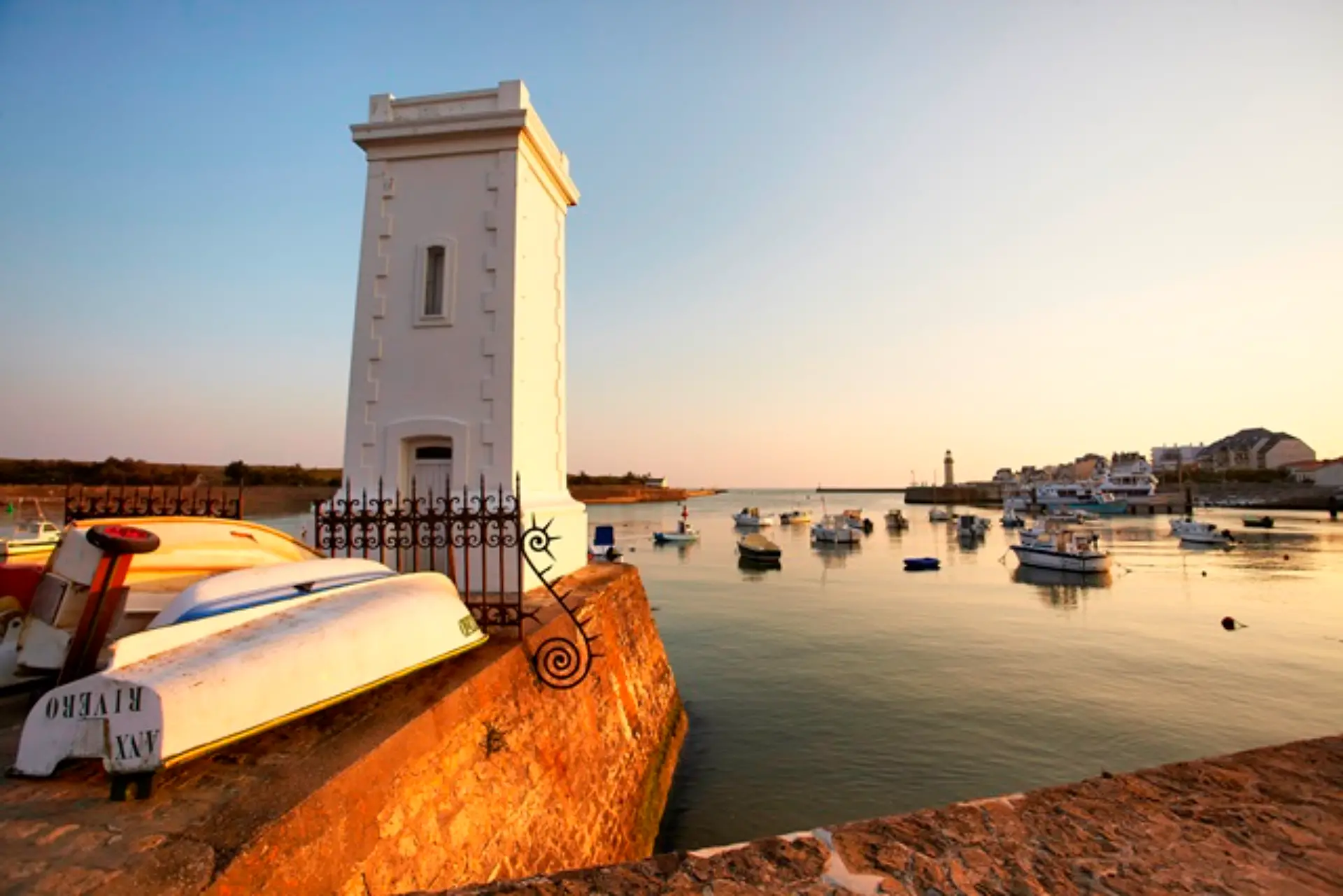 Phare blanc près du port au coucher du soleil.
