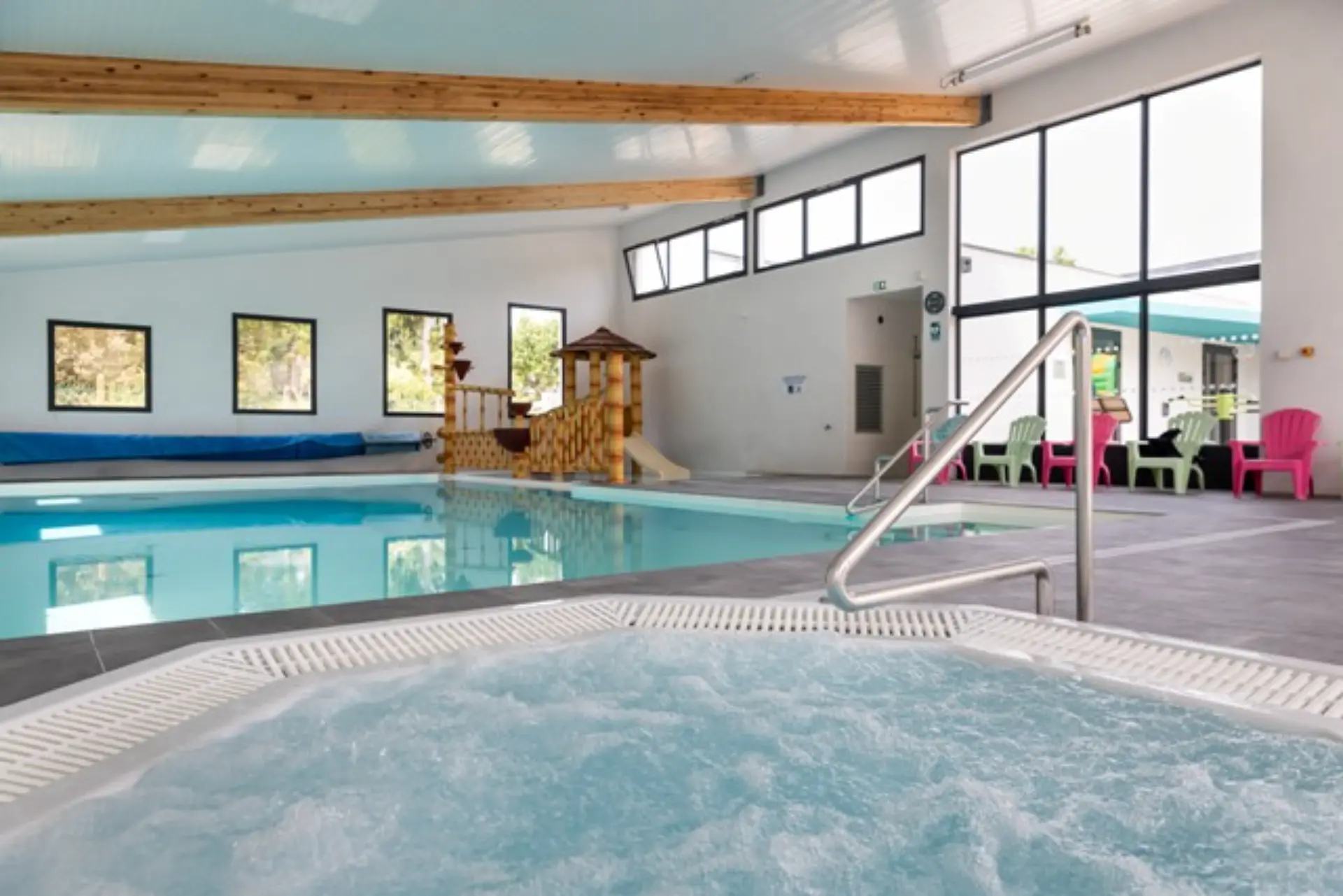 Piscine intérieure avec jacuzzi et chaises longues