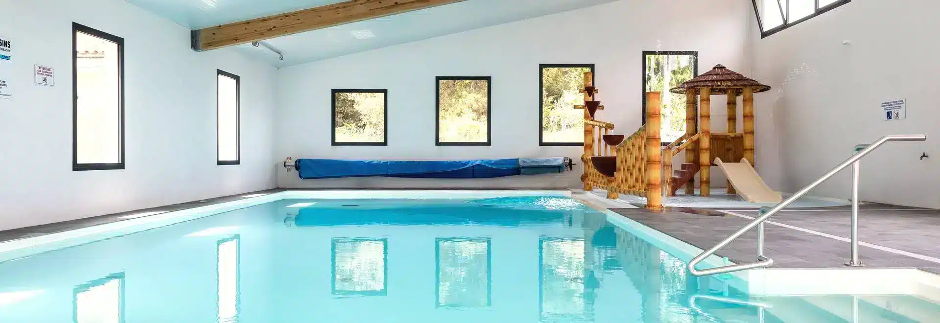 Piscine intérieure avec toboggan en bois.