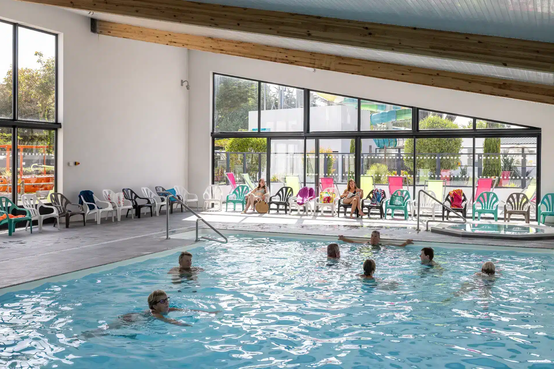 Piscine intérieure avec baigneurs et transats.