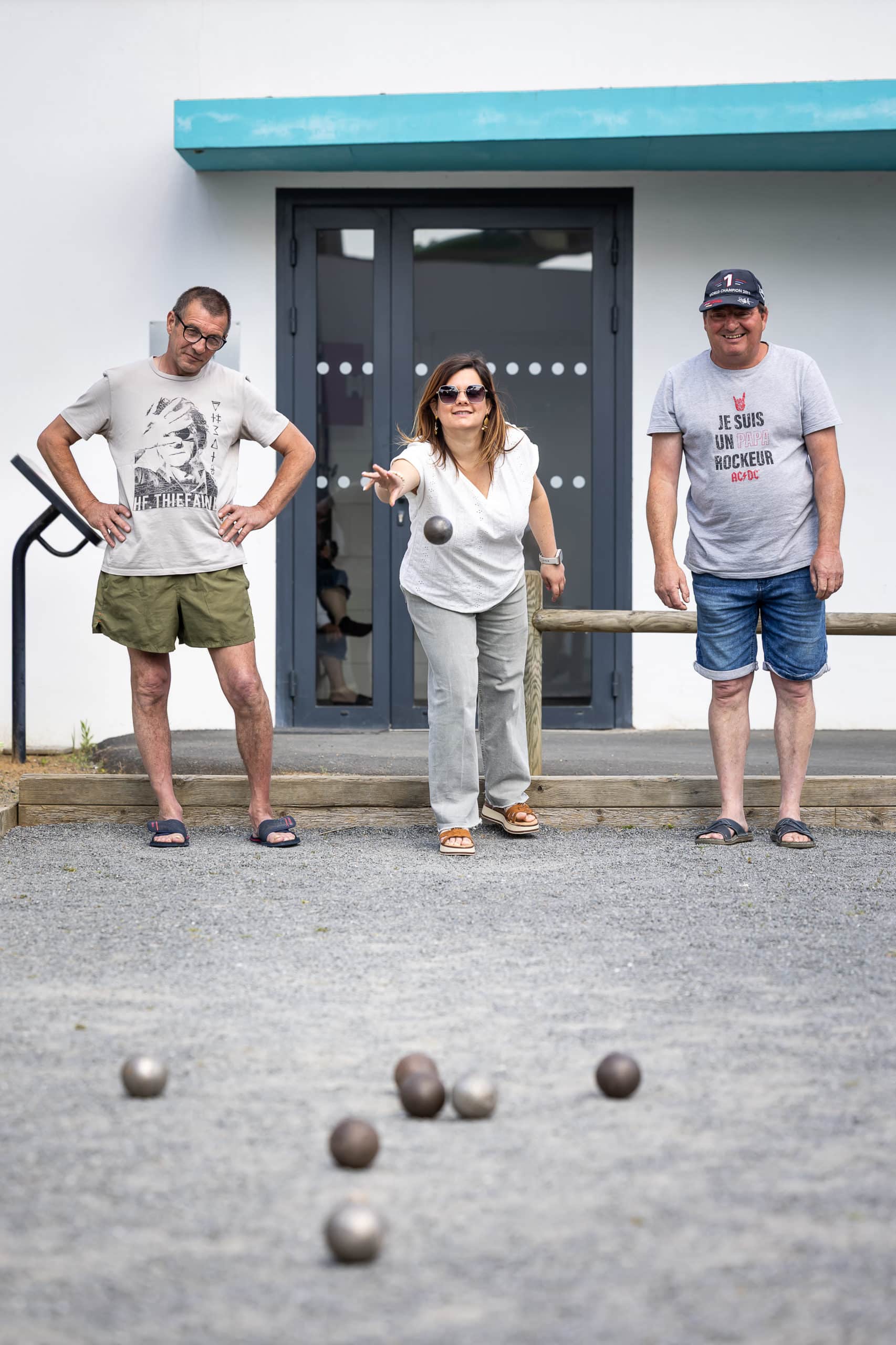 Deux hommes et une femme jouent à la pétanque.